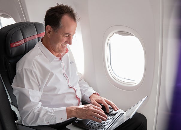 man sitting on a plane typing on computer