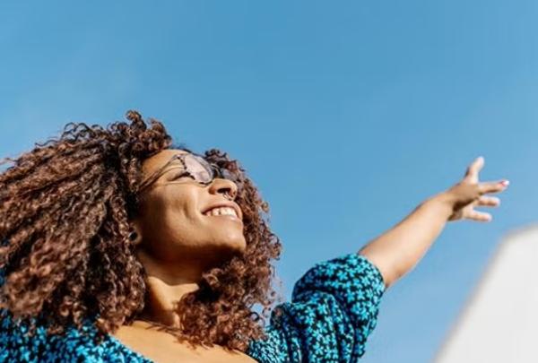 A woman waving here hands in happiness representing Money and stress saving reasons to outsource your business travel.