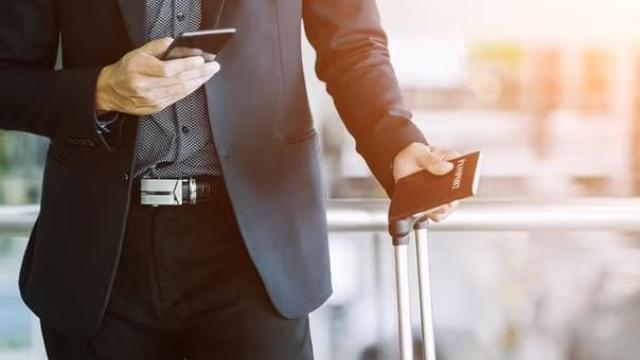 Man holding a smartphone and passwords representing business travel industry.