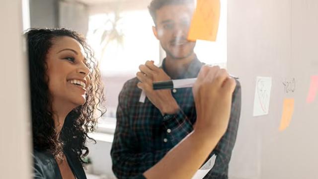 A man and woman talking in the workplace representing travel booker questions asked the most. 