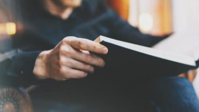 Man reading a book, representing the top personal finance books and podcasts. 