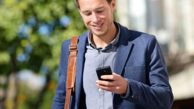 Man walking while looking at phone representing IATA's NDC and it's impact on business travel