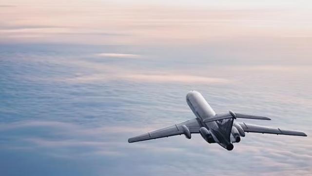 A plane flying over clouds demonstrating the advantages of advance purchase of airfares.