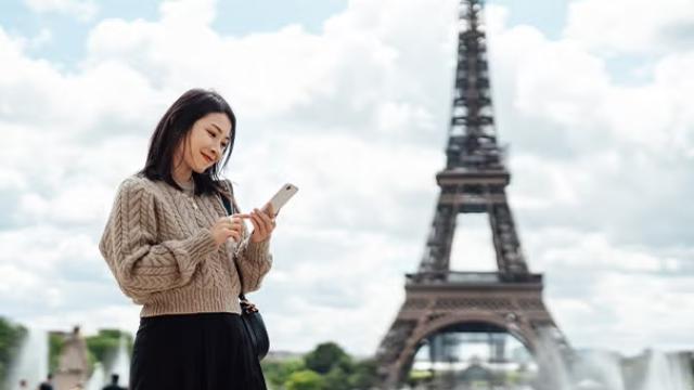 Woman standing by the Eiffel Tower demonstrating ETIAS application requirements before travelling to the EU