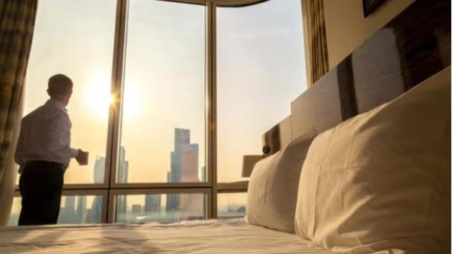 Man looking at city view from hotel room representing the best option for your hotel rates.