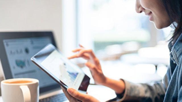 Woman working with a coffee representing use of technology in business travel.