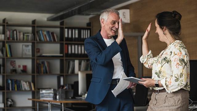 Man and woman giving high five to one another celebrating travel cost savings.