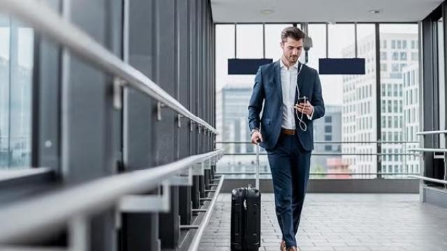 A man walking through the airport with a suitcase demonstrating the benefits of unpacking the basics of business travel.