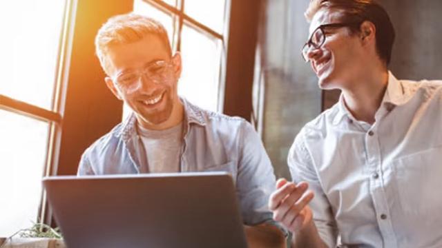 Two men reviewing a laptop, discussing the 2024 Mid-Year Financial Results for FCTG.