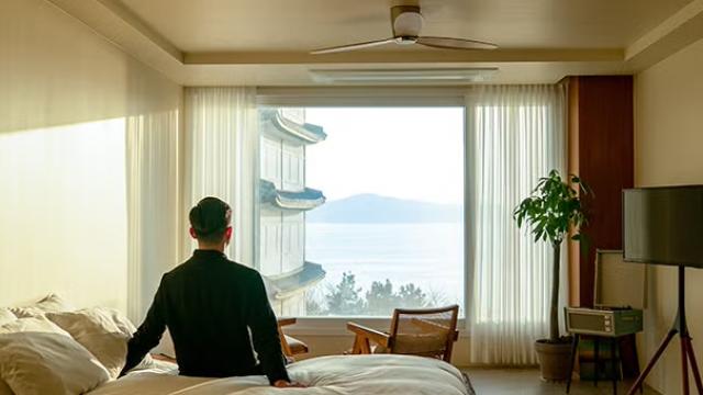 A man sitting on a hotel bed, reflecting the experience of Aussies travelling for work and work-related travel.