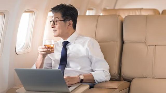 Man sitting on plan in first class showcasing that Business and First Class travel among Australian corporates grew by 43 per cent in 2023 