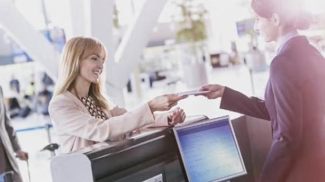 Woman receiving an airline ticket at the ticket desk demonstrating Expert Tips for Improving Air Travel Programs.