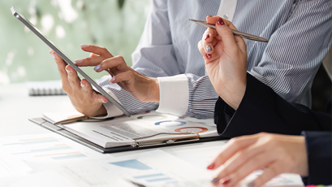 Co-workers reviewing a document representing how Corporate Traveller delivers technology and expense solutions that allow you to manage your travel, get vital information about your travel patterns and stay in control of your travel expenses.