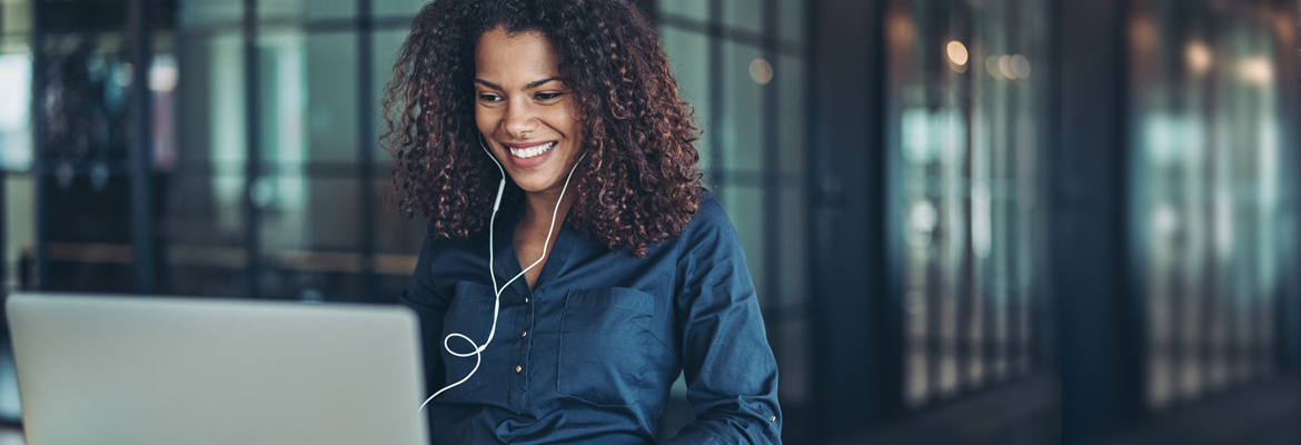 Woman smiling at laptop screen wearing headphones