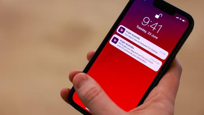 A hand holding a smartphone displaying Virgin Australia's new baggage tracking tool, highlighting a key travel innovation of 2023.