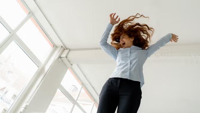 A woman jumping with excitement, celebrating the launch of Up by Corporate Traveller, one of 2023's travel highlights