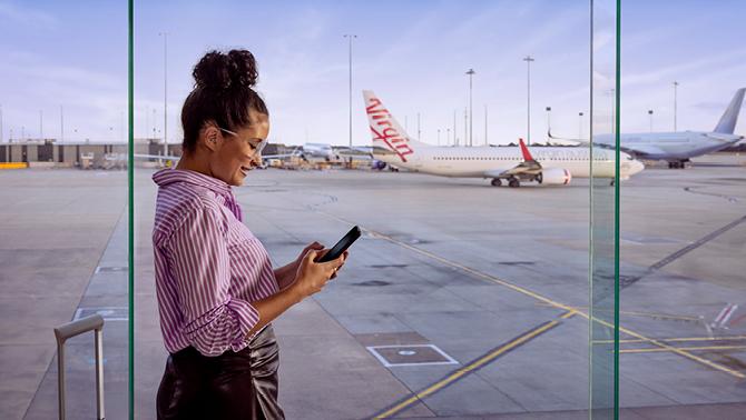 Woman texting on phone in front of aero plane