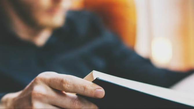 Man reading a book, representing the top personal finance books and podcasts. 