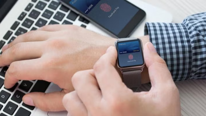 Man working on laptop checking his smartphone representing time-saving with tech.