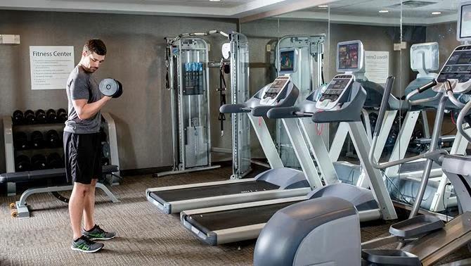 A man lifting weights in a hotel fitness facility as new data reveals a strong emphasis on wellness among business travellers, with a significant portion wanting healthier dining options and well-equipped fitness facilities