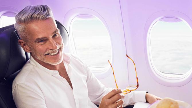 Virgin Airlines Customer sitting in airplane smiling 