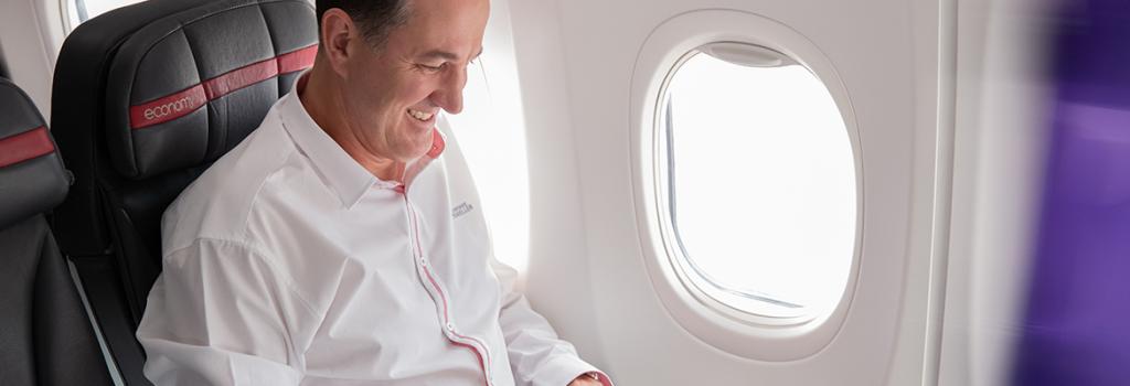 man sitting on a plane typing on computer