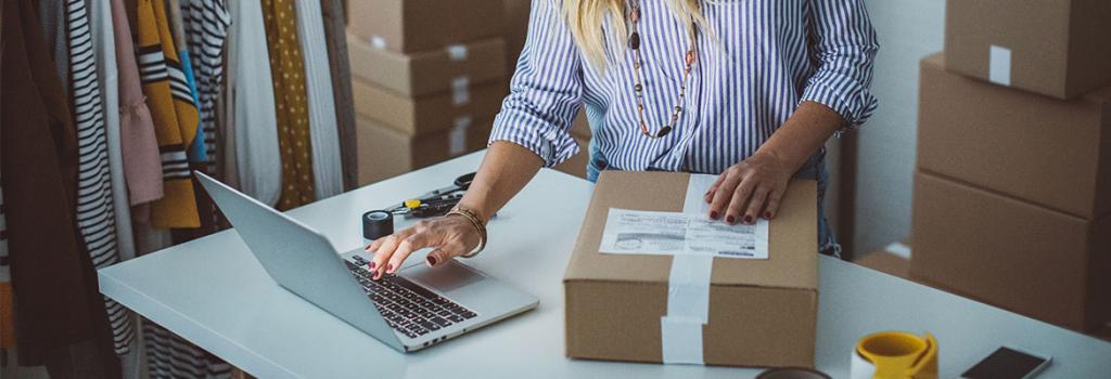 woman holding package and working on laptop