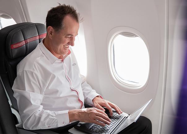man sitting on a plane typing on computer