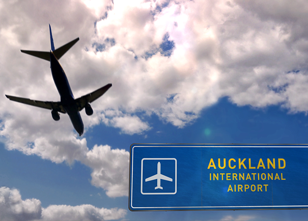 Plane flying through sky with Auckland sign in sight 