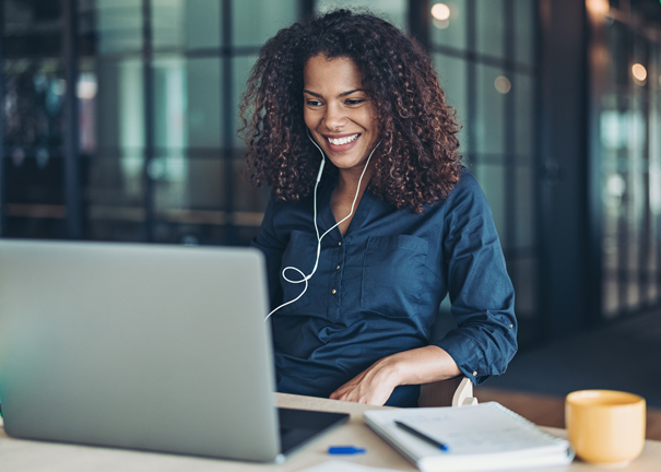 Woman smiling at laptop screen wearing headphones