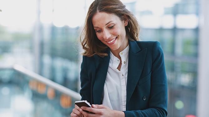A woman looking at her phone, representing a business traveler using a mobile app and online platform for convenience