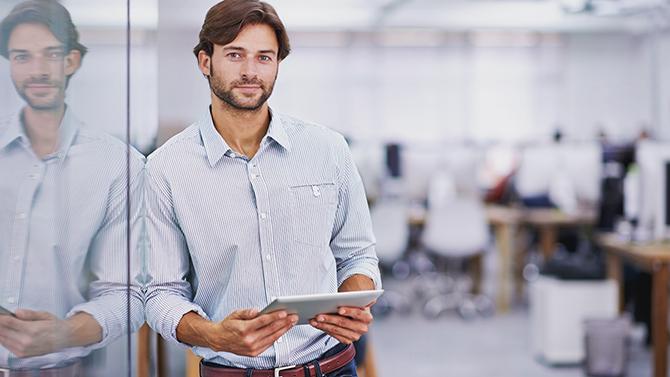 Man standing and holding an iPad, using the CT mobile app for business travel