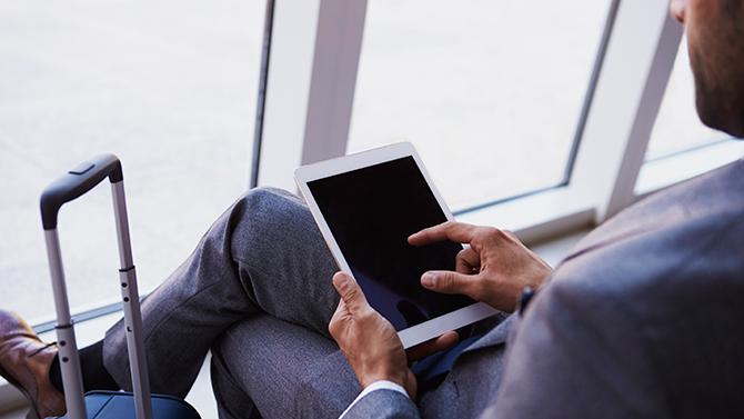 Business traveler sitting with an iPad enjoying the convenience of digital tools for travel