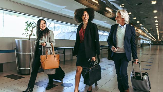 Three women walking through airport with their bags.