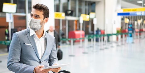 business traveler wearing a mask in an airport, prepared for safe travel