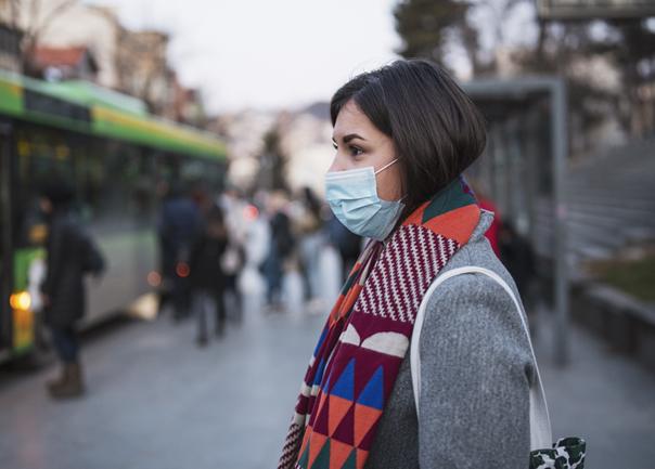 Lady in a mask waiting for Bus