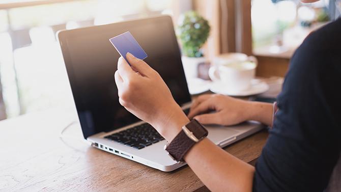 Hands typing on a laptop and using a credit card, representing seamless transactions on your CT business travel management platform
