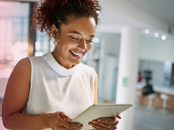 A woman looking at an iPad, highlighting the blend of business travel tech, automation, and human assistance for streamlined travel management