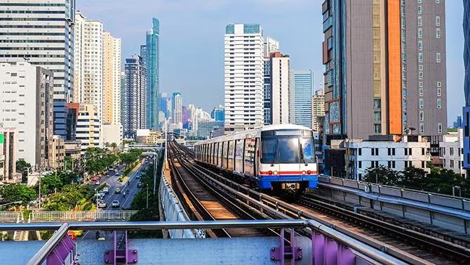 Moving train with the city of Bangkok in the background, showcasing tourist attraction in the Bangkok travel guide.