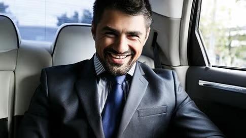 Man sitting at the back of the car representing a specific business traveller type. 