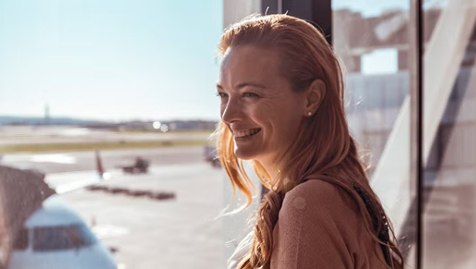 Woman looking out the window at the airport representing the importance of a corporate travel partner.