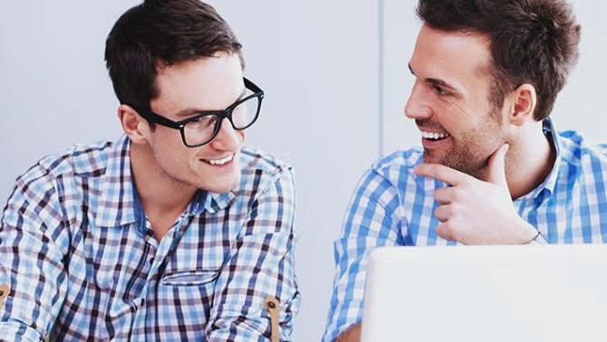 Two co-workers talking excitedly while looking at a laptop demonstrating how making some simple tweaks to its booking processes pulled Diadem out of its last minute booking compulsion.