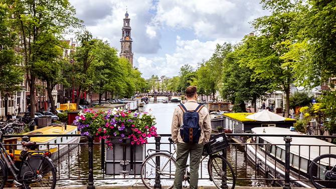 Man standing on a bridge in Amsterdam looking at the view demonstrating ETIAS application requirement before travelling to the EU