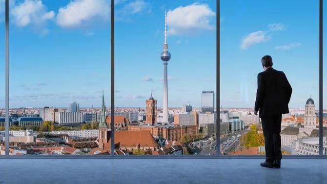 Man looking out of a window to a cityscape view, showcasing tourist attractions as part of a destination travel guide.