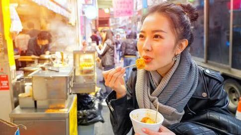 Woman enjoying a meal at an outdoor food vendor, showcasing tourist attractions in the Hong Kong destination travel guide.