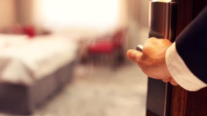 Man opening the door of a hotel room, showcasing tourists attractions in the Melbourne travel destination guide.