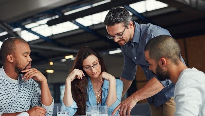 Co-workers reviewing documents on table Woman holding laptop standing outside representing the importance of elevating your company’s travel program.