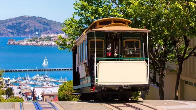 A tram with a backdrop of the city of Fransisco, showcasing tourist attractions in the San Fransisco travel destination guide.