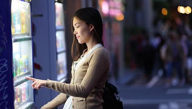 Woman buying an item out of a vending machine representing Tokyo destination travel guide.