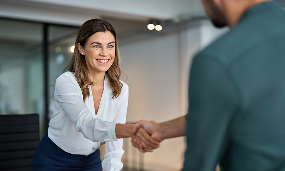 A man and woman shaking hands representing how Corporate Travellers Expert Onboarding program ensures a solid foundation for your new travel program and makes change management quick and easy.